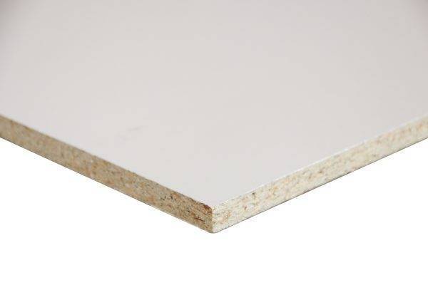 Corner of a white laminated particleboard panel with the exposed wood-core edge showing its brown, speckled composition.