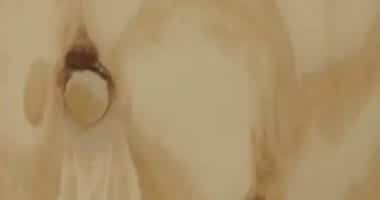 Close-up of a beige-toned abstract painting with a dark circular shape toward the left edge.